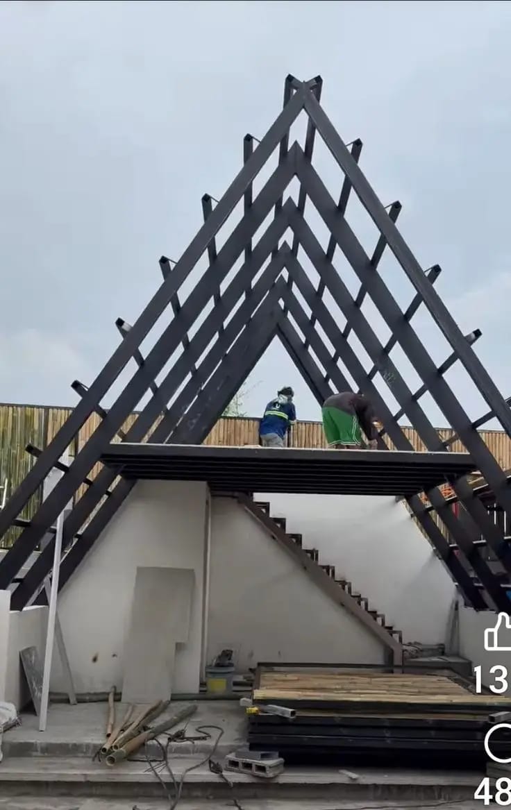 Workers building an A-frame steel structure with a staircase