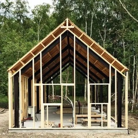 Timber frame house under construction in a forest setting